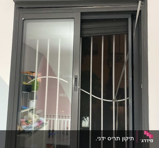 חלון עם תריסים אפורים סגורים למחצה